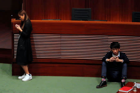 Newly elected pro-democracy lawmakers Yau Wai-ching and Baggio Leung check their smartphones after taking oath at the Legislative Council. REUTERS/Bobby Yip