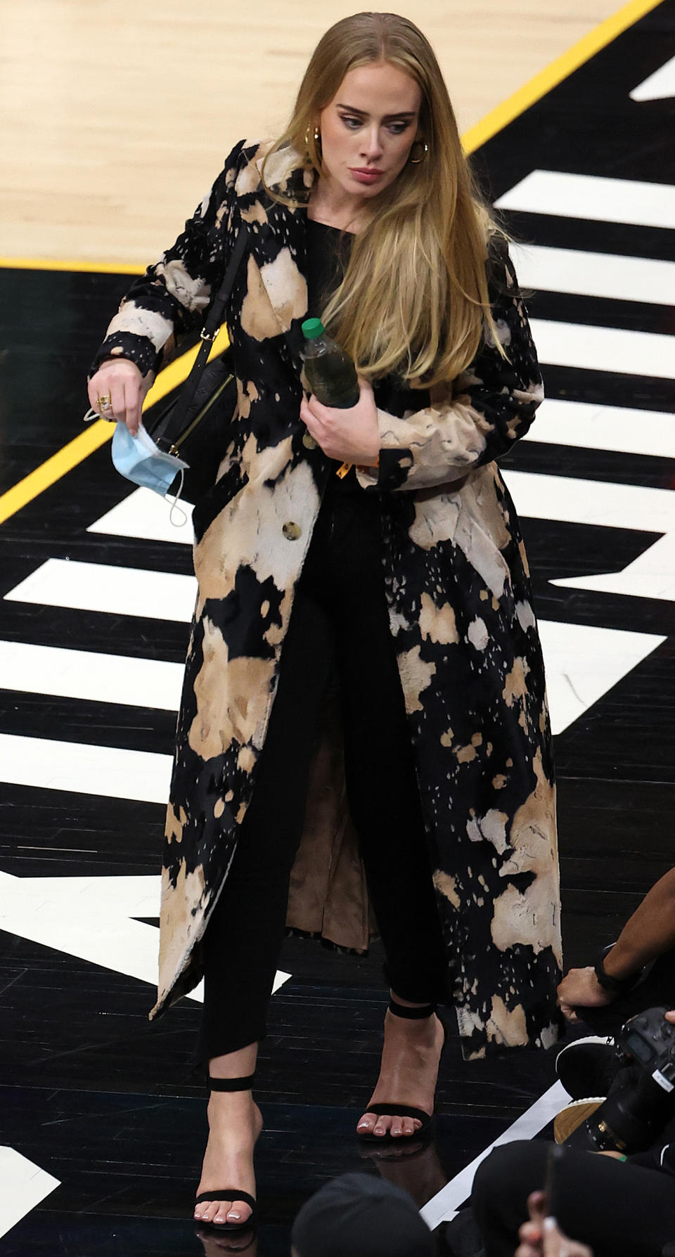 Adele sported a long neutral patterned jacket over a monochromatic black ensemble, including a simple sleek top and a pair of leggings.