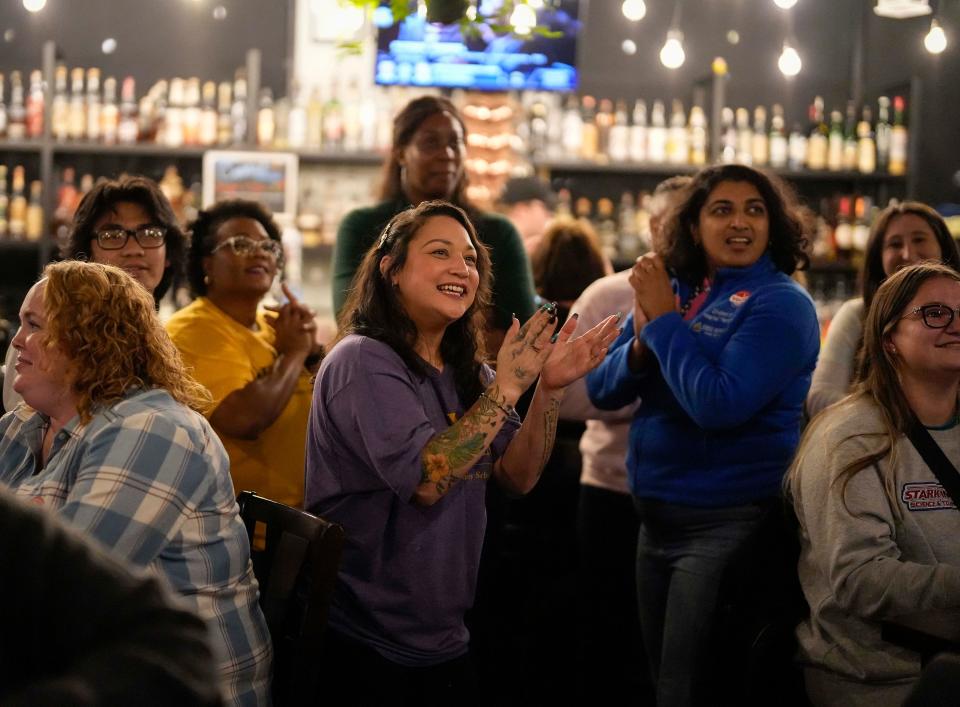 Temeshia Bomato, owner of Pots and Shots, center, cheers alongside supporters of a slate of four progressive-endorsed Johnston school board candidates as numbers roll in during a watch party in West Des Moines on Nov. 7.