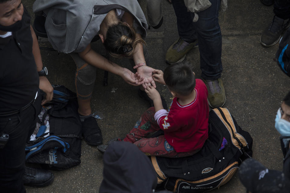 A migrant adult and child sit in the patio at the Attorney Generals Office after they were intercepted from inside cargo trailer trucks driving on the highway, in Coatzacoalcos, Veracruz state, Mexico, Friday, Nov. 19, 2021. About 500 migrants were riding in two cargo trucks when they were stopped and detained by the Criminal Investigation Agency and the National Immigration Institute, according to those two organizations. (AP Photo/Felix Marquez)