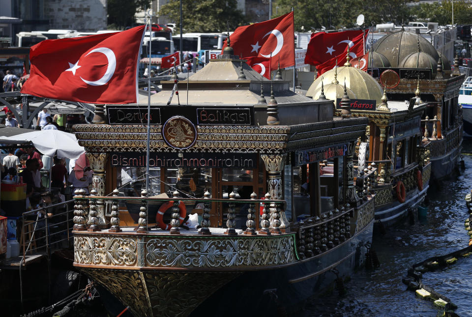 In this Monday, Aug. 20, 2018 photo, boats offering fish delicacies are docked by the Golden Horn, leading to the Bosporus Strait, in Istanbul. Tourists have returned in droves to Turkey according to the government figures, helped this summer by the sharp fall in the value of the Turkish lira following economic uncertainty and a rift with the United States. (AP Photo/Lefteris Pitarakis)