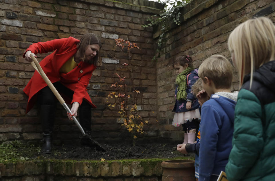 Britain's Liberal Democrats leader Jo Swinson finishes off planting an Acer tree in the garden of the Razumovsky music Academy watched by children of party supporters, as she campaigns in the Hampstead and Kilburn constituency in north London, Saturday, Nov. 16, 2019. Britain goes to the polls on Dec. 12. (AP Photo/Matt Dunham)