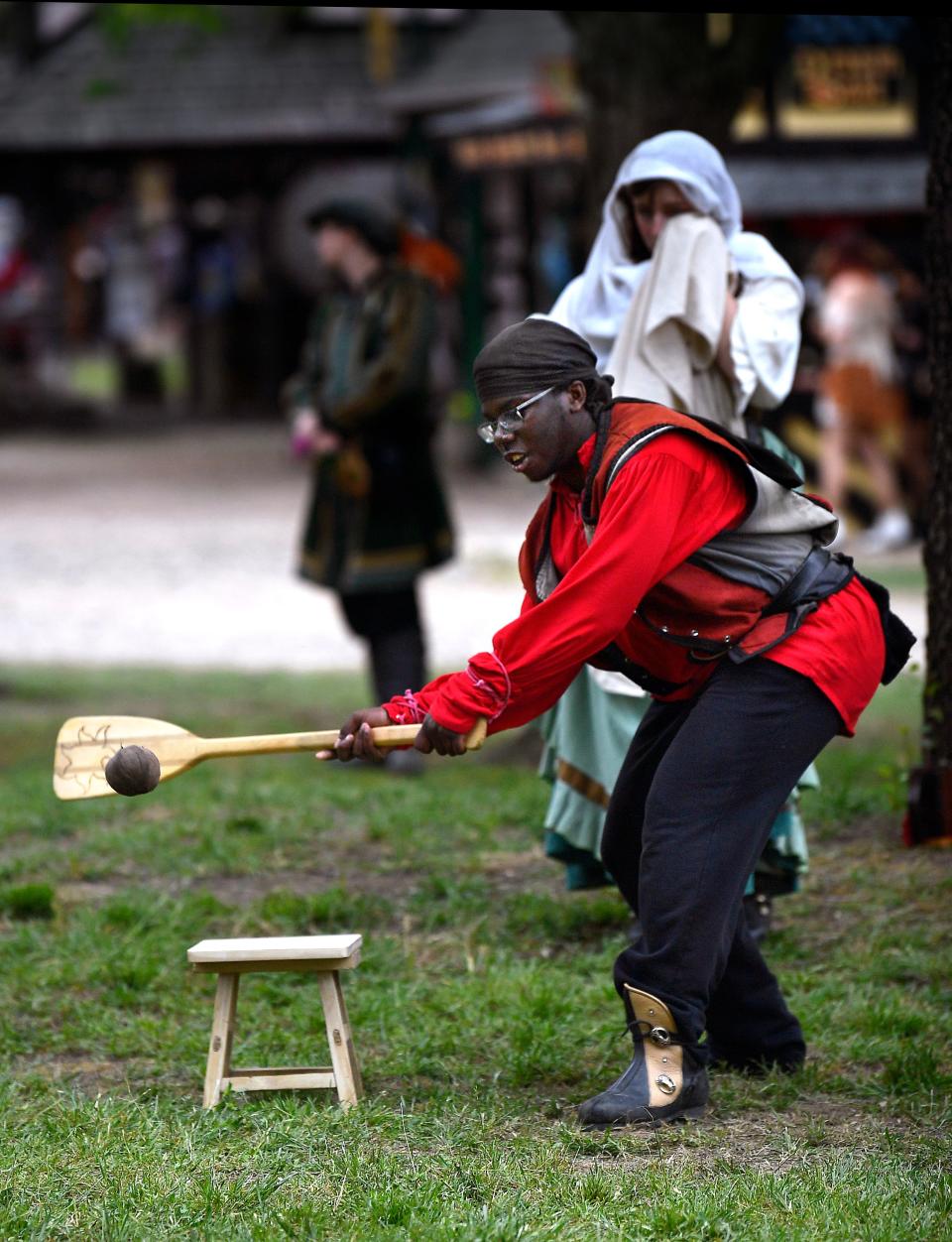 Bakari Boardman connects using a canoe paddle during a game of Stool Ball at Scarborough Renaissance Festival.