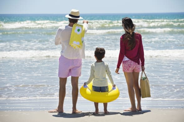 Boy with his parents looking at sea on the beach