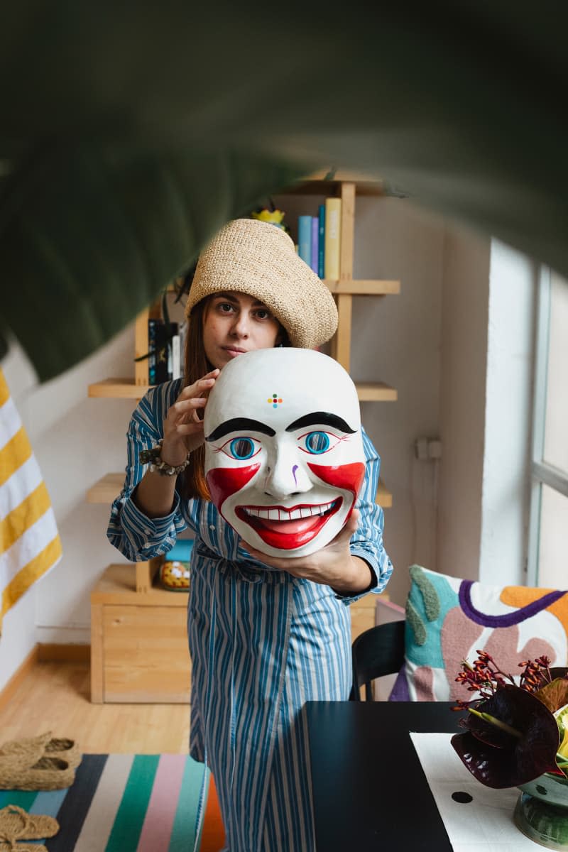 Dweller holds mask next to cafe table.