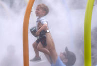 Tennis - Australian Open - First Round - Melbourne Park, Melbourne, Australia, January 15, 2019. A spectator holds up a child at a water spray to cool down during the Australian Open. REUTERS/Aly Song