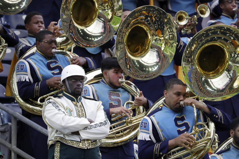 A member of the Norfolk State University Spartan Legion marching band, in white, stands next to the tuba section of the Southern University Human Jukebox marching band as they perform in the stands during the 2023 National Battle of the Bands, a showcase for HBCU marching bands, held at NRG Stadium, Saturday, Aug. 26, 2023, in Houston. (AP Photo/Michael Wyke)