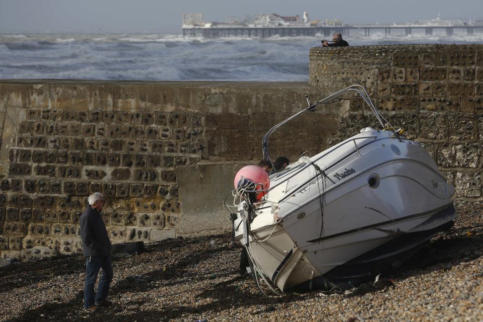 A man walks alongside a yacht washed up on the beach after storms battered Brighton in south east England October 28, 2013. Britain's strongest storm in a decade battered southern regions on Monday, forcing hundreds of flight cancellations, cutting power lines and disrupting the travel plans of millions of commuters. (REUTERS/Luke MacGregor)