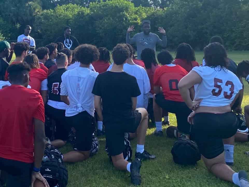Palm Beach Central football players gather around head coach Kevin Thompson for the first knee of the 2023 season at practice on Monday, July 31.