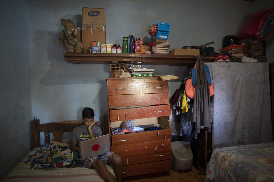 Samuel Andres Mendoza sits in his room with a laptop, gifted to him by his social media followers, at his home in Barquisimeto, Venezuela, Tuesday, March 2, 2021. After the 14-year-old tweeted to sell his drawings to buy food, an artist gave him a scholarship to study drawing, and social media followers sent him a set of artists' pencils and food. (AP Photo/Ariana Cubillos)