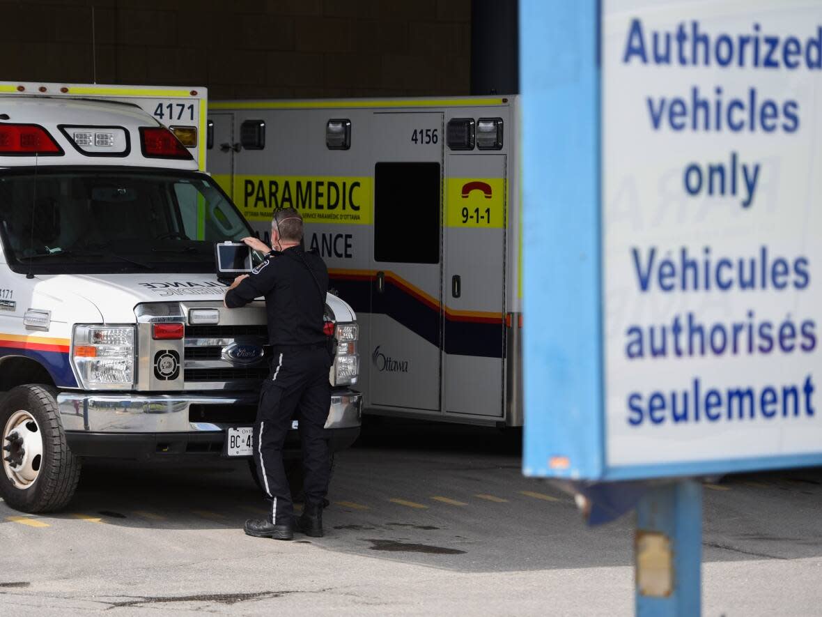 A paramedic works on a laptop on the hood of their ambulance outside The Ottawa Hospital's Civic campus May 16, 2022. (Justin Tang/The Canadian Press - image credit)