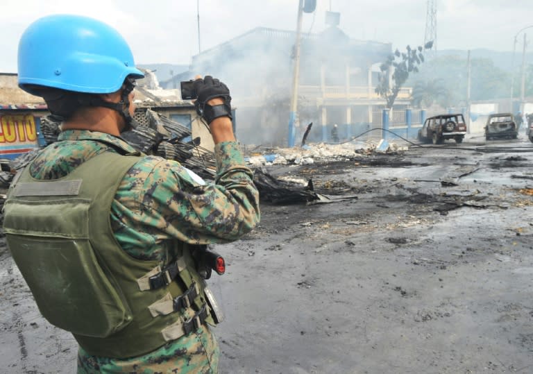 A UN peacekeeper inspects the aftermath of a 2013 blaze that swept through a market in Port-au-Prince