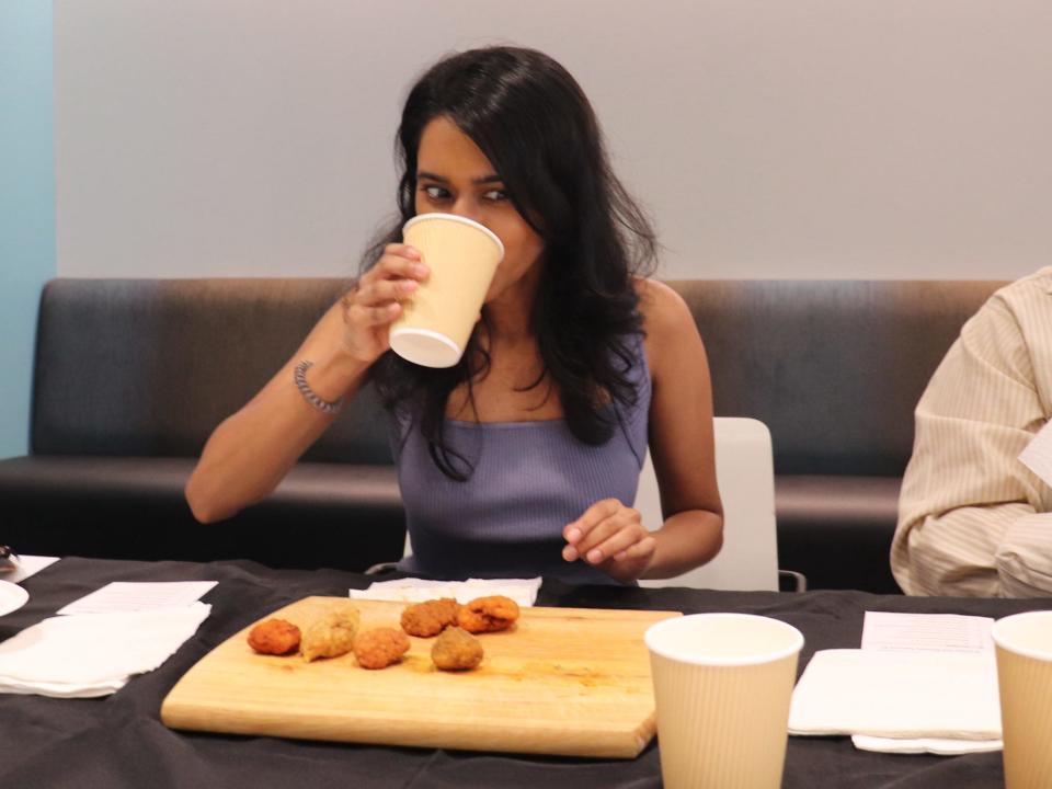 Two of Insider's reporters eating hot wings and drinking milk.