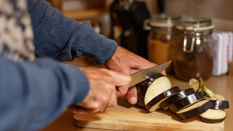 slicing eggplant on cutting board
