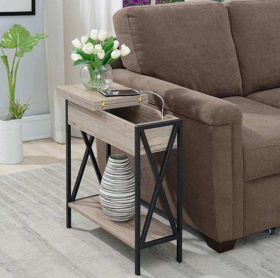 Side table with phone charger inside next to brown couch