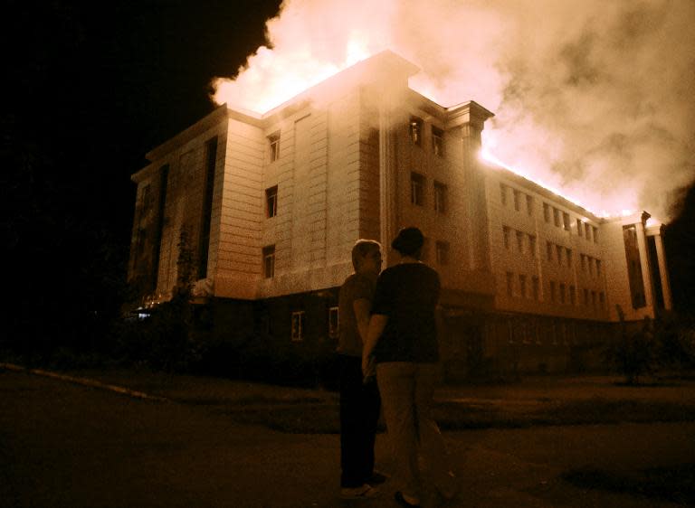 Bystanders watch a fire consuming a school in downtown Donetsk on August 27, 2014, after being hit by shelling