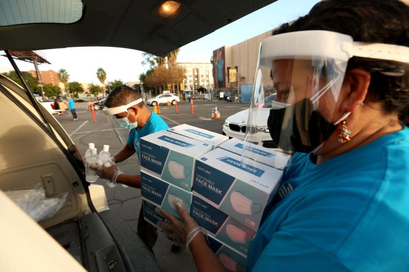 HOLLYWOOD, CA - DECEMBER 26, 2020 - Gisela Mora, right, and Miguel Gonzalez, both with PPE Unite, load up a car with free masks, bottles of hand sanitizers and other PPE materials for small business owners in a parking lot along Hawthorn Avenue in Hollywood on December 26, 2020. PPE Unite, the L.A. County Department of Workforce Development, Aging and Community Services, the Los Angeles Small Business Development Center network and the Hollywood Chamber of Commerce handed out PPE materials to help protect small businesses in Los Angeles County to stay protected and open for business with a FREE 30-day supply of PPE. "As businesses face adversity with the on-going health and economic crisis, our goal is to ensure that businesses don't have further burdens to their bottom line with the purchasing of PPE materials during this pandemic crisis," said Jay Taso, CEO of Logisticom and Co-Lead at PPE Unite. "Through this collaborative partnership with the Hollywood Chamber of Commerce, businesses in the Hollywood area will receive the necessary supplies to help them to create a safe work environment." To date, PPE Unite has signed up more than 750 businesses for this weekend's one-day event in Hollywood and over 25,000 small businesses since the launch of this initiative. Additionally, 4 million units of PPE masks and over 500,000 units of sanitizer have already been distributed since the launch of this initiative two months ago. (Genaro Molina / Los Angeles Times)