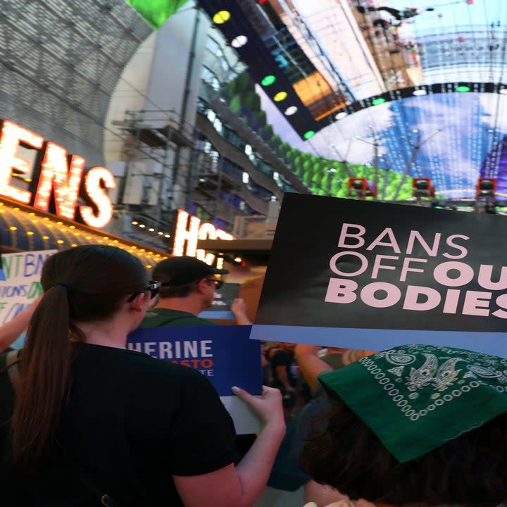 crowd of people with bans off our bodies signs marching down the strip