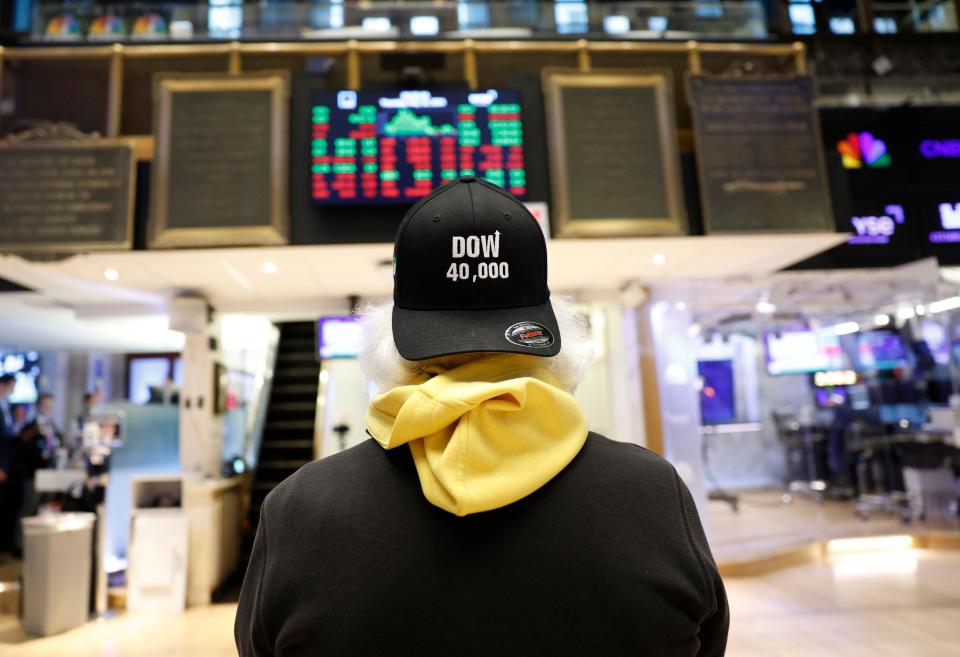 A trader on the floor of the New York Stock Exchange, Wall Street and FTSE were lower