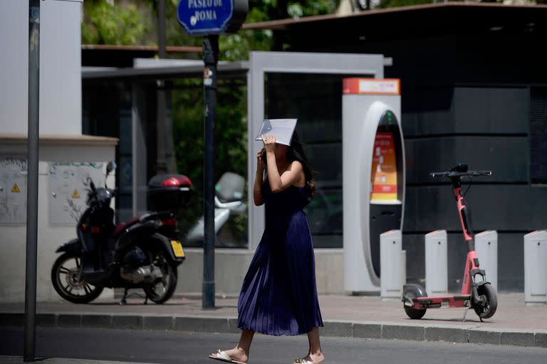Una mujer se cubre la cabeza mientras camina durante una ola de calor en Sevilla el 10 de julio de 2023