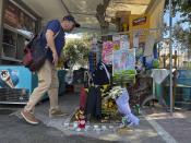 A man lays flowers, on the location where a 29-year-old Greek fan has died after overnight clashes between rival supporters in Nea Philadelphia suburb, in Athens, Greece, Tuesday, Aug. 8, 2023. European governing soccer body UEFA says it has postponed a Champions League qualifying game between AEK Athens and Croatia's Dinamo Zagreb scheduled for Tuesday because of the violence. Eight fans were injured while Greek police said Tuesday they had made 88 arrests, mostly of Croatian supporters. (AP Photo/Thanassis Stavrakis)