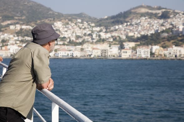 greece, northern aegean, samos, vathy. tourist rests on handrail on deck of ferry between samos and kusadasi in turkey as it lea