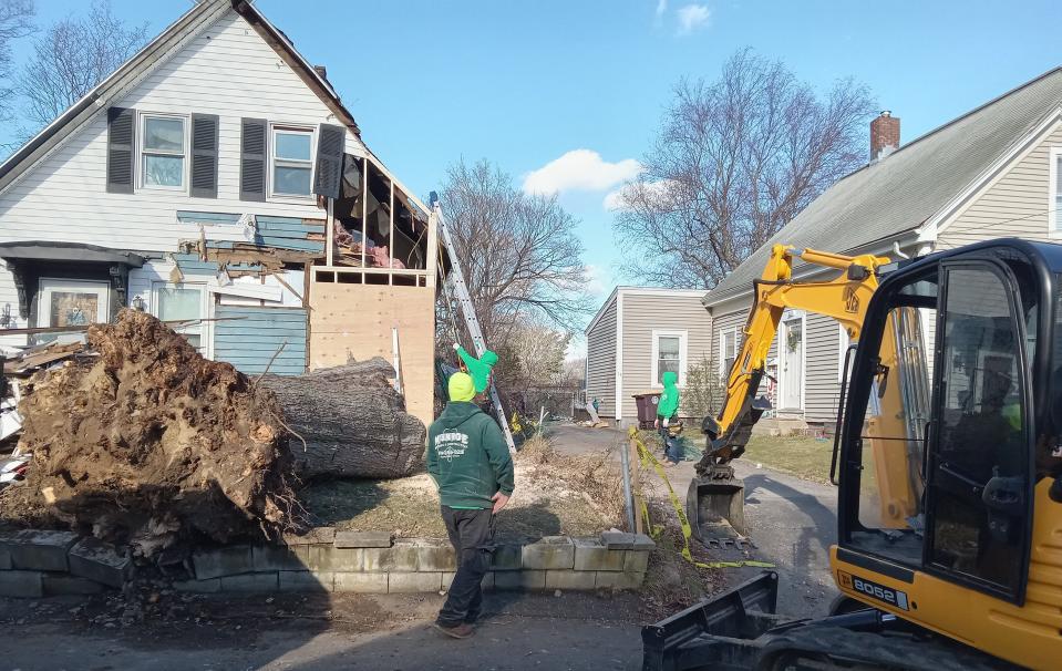 Nick Munroe, owner of Munroe Roofing and Construction, supervises workers as they repair a damaged home on Franklin Street in Weymouth that was hit by a felled tree during Monday's storm.