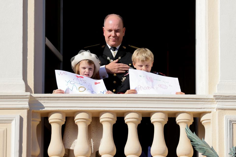Prince Albert II of Monaco, Princess Gabriella and Prince Jacques stand with a message for Princess Charlene at the balcony of Monaco Palace during the celebrations marking Monacos National Day in Monaco, on November 19, 2021. (Photo by Valery HACHE / AFP) (Photo by VALERY HACHE/AFP via Getty Images)
