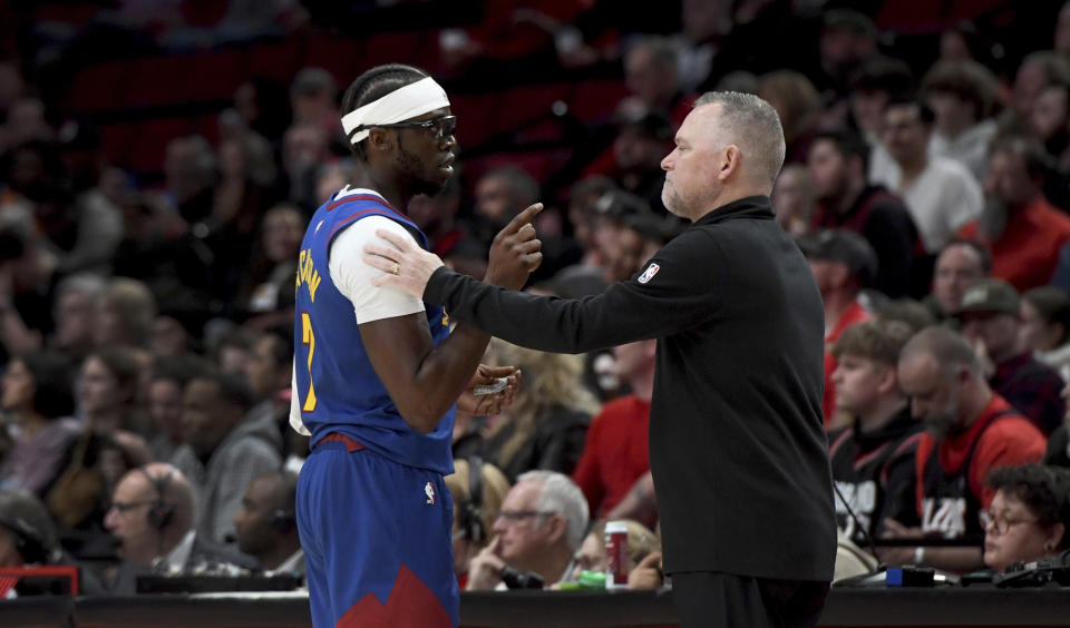 Denver Nugget head coach Michael Malone, right, speaks with guard Reggie Jackson, left, during the first half of an NBA basketball game against the Portland Trail Blazers in Portland, Ore., Friday, Feb. 23, 2024. (AP Photo/Steve Dykes)