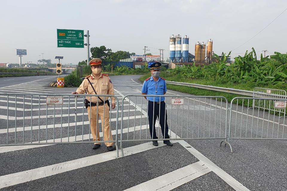 Policemen guard behind barricades set up to control the traffic in Hanoi, Vietnam, Saturday, July 24, 2021. Vietnam announced a 15-day lockdown in the capital Hanoi starting Saturday as a coronavirus surge spread from the southern Mekong Delta region. (AP Photo/Hieu Dinh)