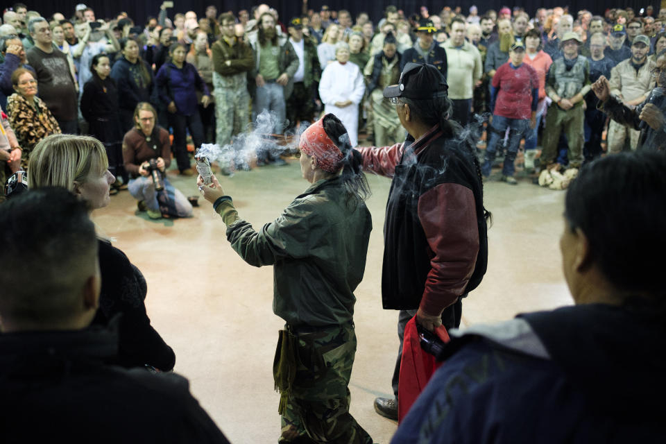 U.S. Army Veterans Tih Kobolson, left, and Aloysious Bell, walk around with a ceremonial smudge stick and feathers during a forgiveness ceremony at the Four Prairie Knights Casino &amp; Resort on the Standing Rock Sioux Reservation on Monday.