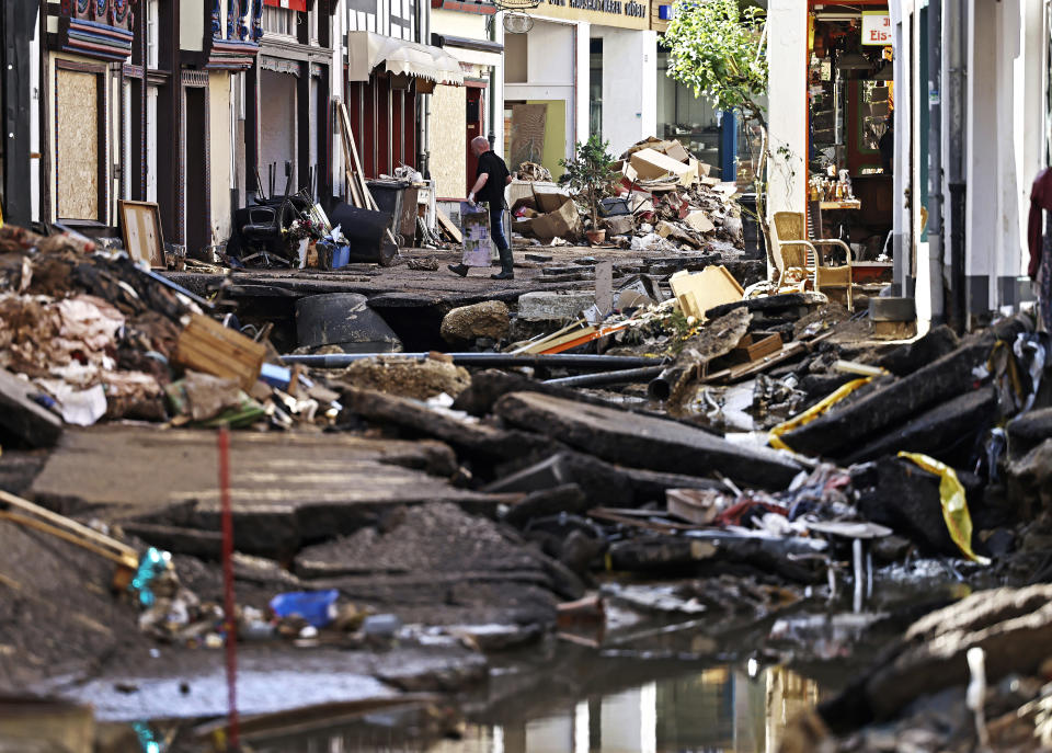 A man carries debris out of a house in Bad Muenstereifel, western Germany, Sunday, July 18, 2021. Heavy rains caused mudslides and flooding in the western part of Germany. Multiple have died and are missing as severe flooding in Germany and Belgium turned streams and streets into raging, debris-filled torrents that swept away cars and toppled houses. (Oliver Berg/dpa via AP)