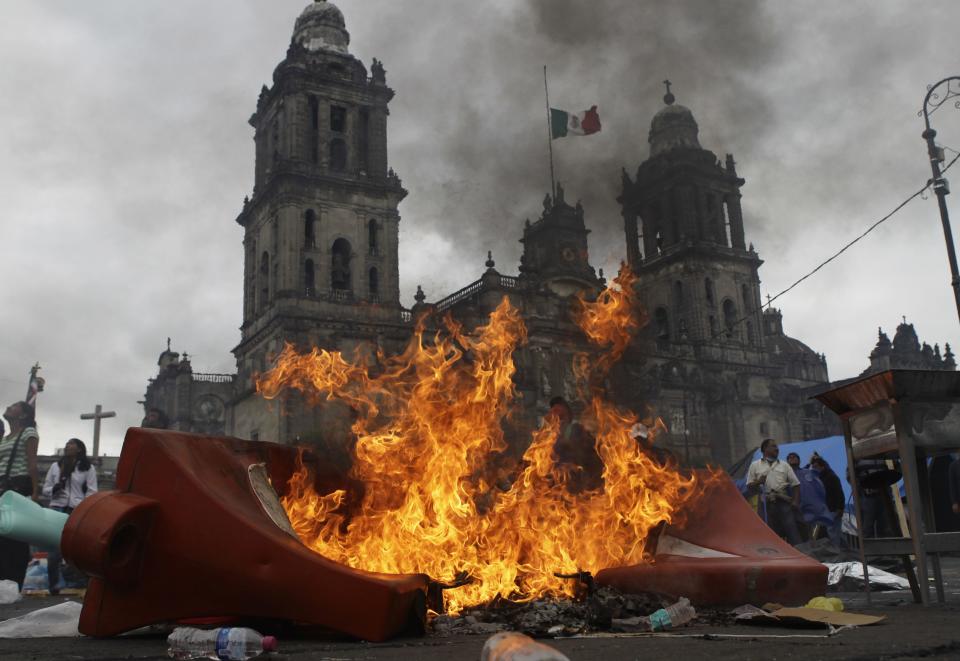 Members of the teachers' union CNTE and protesters stand near a burning barricade before they are evicted from Zocalo Square by the riot police in downtown Mexico City September 13, 2013. (REUTERS/Henry Romero)