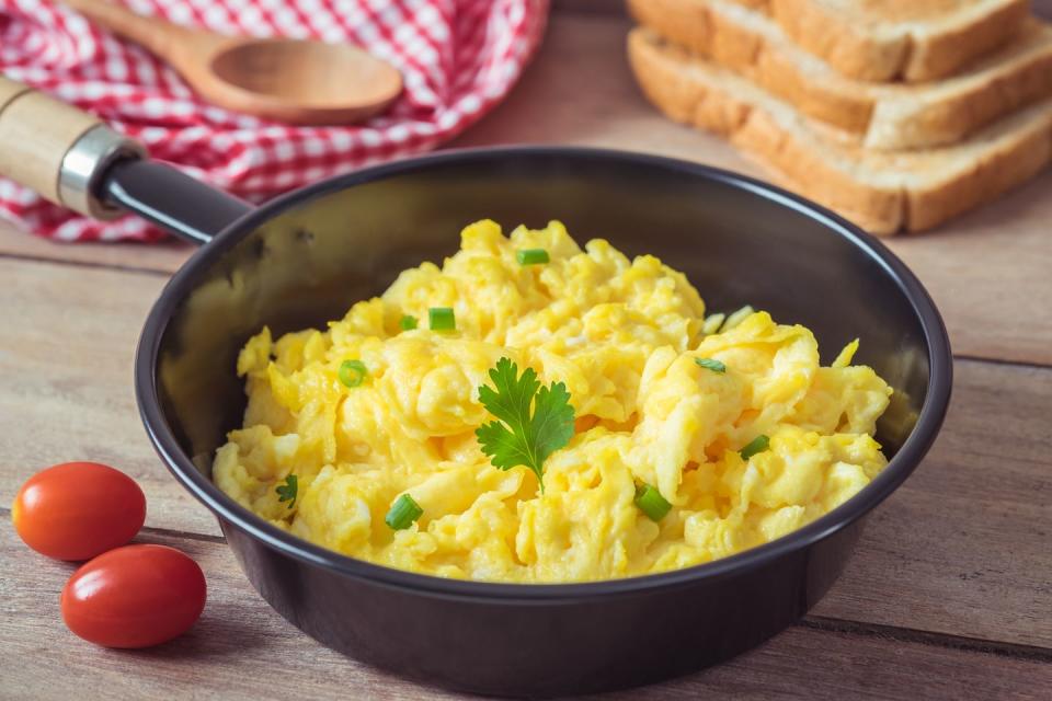 scrambled egg in frying pan and toast on wooden table for good housekeeping's best high calorie snacks