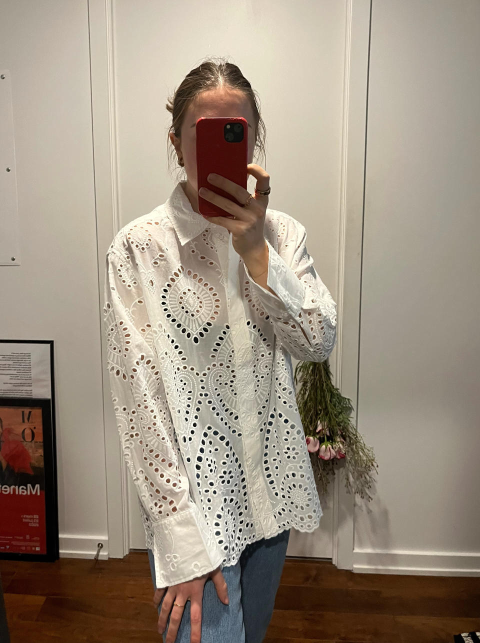 woman taking mirror selfie in white eyelet lace top and blue jeans