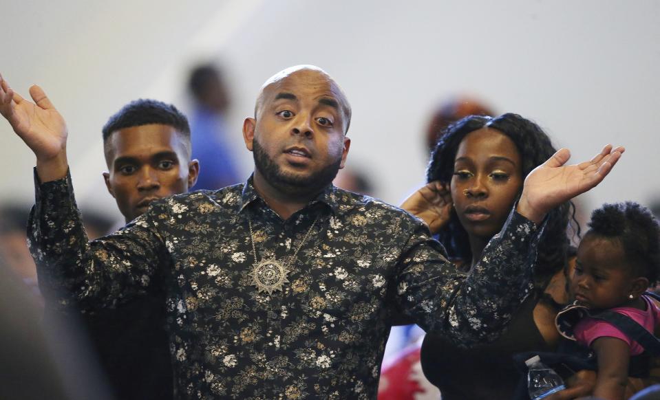 FILE - In this June 18, 2019, file photo, Rev. Jarrett Maupin, front, gestures in frustration as he arrives with Dravon Ames, left, Lesha Harper, second from right, and one of the family's two daughters, 1-year-old London, right, prior to the start of a community meeting in Phoenix. The community meeting stemmed from reaction to a videotaped encounter that surfaced recently of Ames and his pregnant fiancee, Harper, having had guns aimed at them by Phoenix police during a response to a shoplifting report, as well as the issue of recent police-involved shootings in the community. The Phoenix Police Department says it will train officers to track when they point their guns at people. The department announced Friday, Aug. 2 the policy was recommended by the Community Police Trust Initiative and the National Police Foundation, which studied last year's police shootings in the city. The policy will go into effect Aug. 19. (AP Photo/Ross D. Franklin, File)