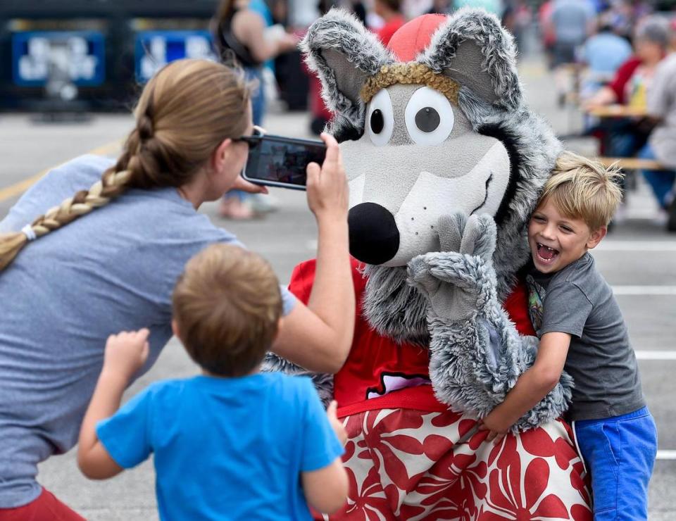 Five-year-old Emmett Stutz poses with KC Wolf as his mother Carrie Stutz takes a photo and Emmett’s brother Thomas Stutz, 4, tries to get a look. The three-day Kansas City BBQ Festival in the parking lot of the GEHA Field at Arrowhead Stadium concluded Sunday, July 11, 2021.