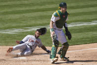 Detroit Tigers' Willi Castro, left, slides home to score behind Oakland Athletics catcher Sean Murphy during the sixth inning of a baseball game in Oakland, Calif., Sunday, April 18, 2021. (AP Photo/Jeff Chiu)