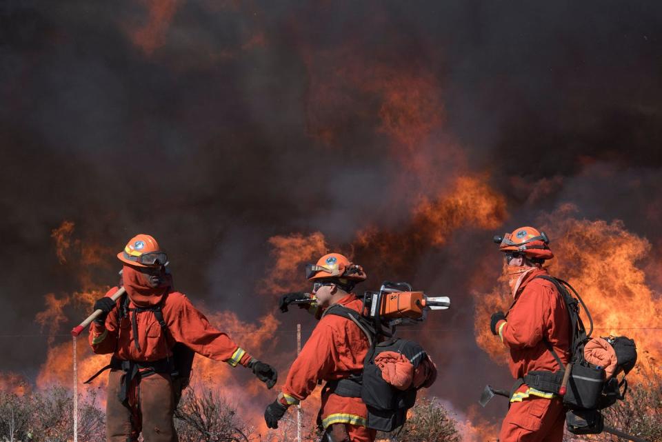 <span class="caption">Inmate firefighters prepare to put out flames in Simi Valley, California, on October 30, 2019.</span> <span class="attribution"><a class="link " href="https://www.gettyimages.com/detail/news-photo/inmate-firefighters-prepare-to-put-out-flames-on-the-road-news-photo/1179075943?adppopup=true" rel="nofollow noopener" target="_blank" data-ylk="slk:Photo by Mark Ralston/AFP via Getty Images;elm:context_link;itc:0;sec:content-canvas">Photo by Mark Ralston/AFP via Getty Images</a></span>