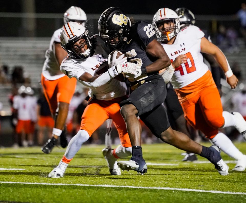 Golden Gate Titans running back Trayvon jean (22) muscles past Lely Trojans cornerback Osyrus Boykin (7) for a touchdown during the first quarter of a district game at Golden Gate High School in Naples on Friday, Oct. 27, 2023.