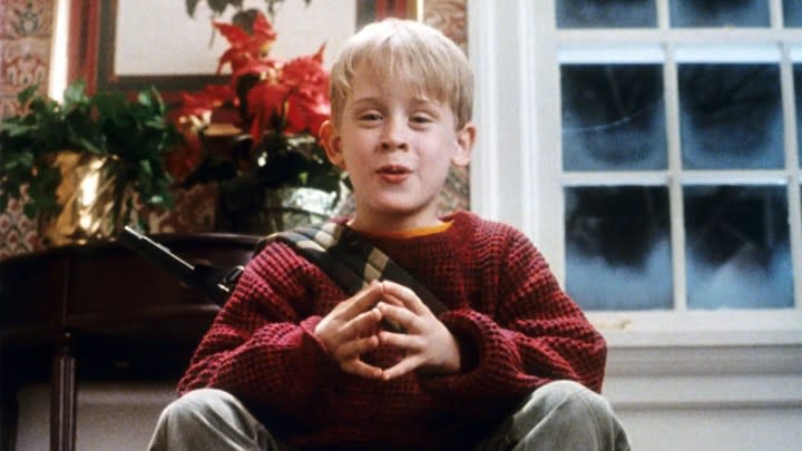 A young boy sits on steps with a gun in "Home Alone."