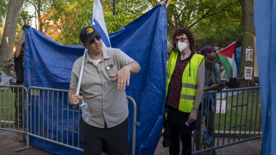 A tarp is held up to shield the encampment from a counter protester. - Evelio Contreras/CNN