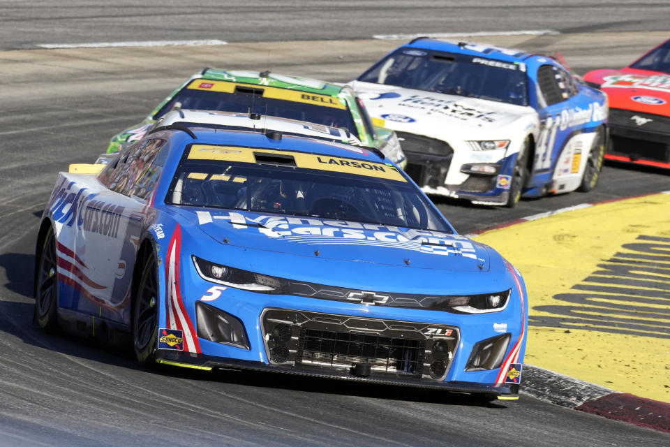 Kyle Larson (5) leads Christopher Bell (20) out of Turn 2 during a NASCAR Cup Series auto race at Martinsville Speedway in Martinsville, Va., Sunday, Oct. 29, 2023. (AP Photo/Chuck Burton)