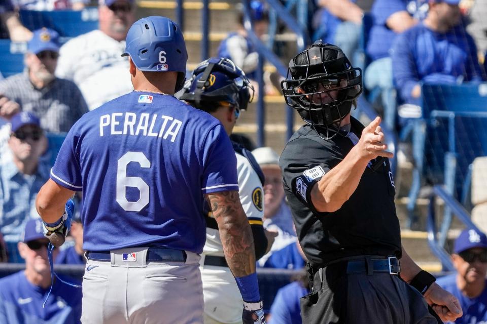 Home plate umpire Jim Wolf tells Dodgers' David Peralta to take a base after a pitching clock violation.