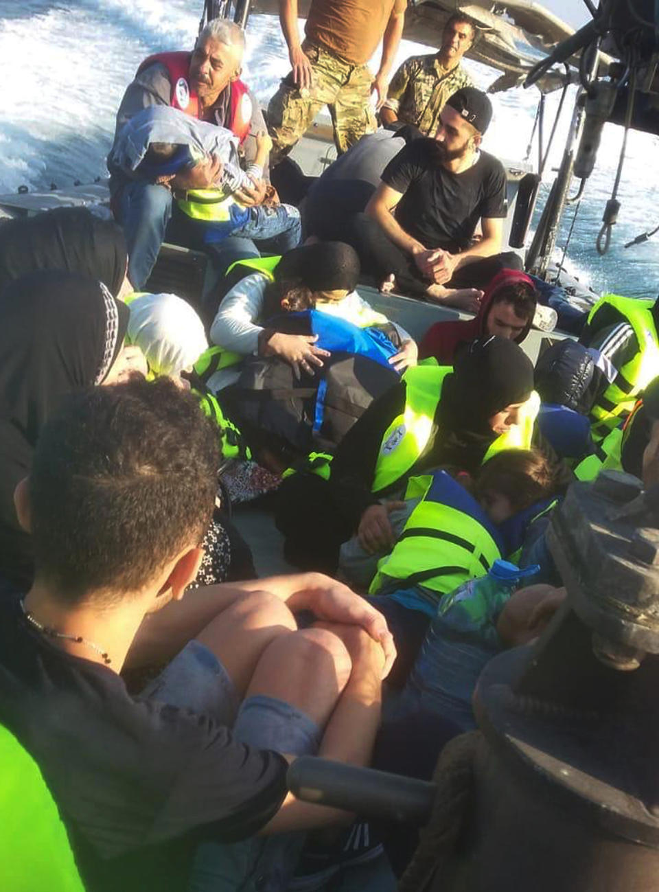 In this photo released by the Lebanese Army official website, shows rescued migrants sit on a Lebanese army boat after their boat capsized off the Lebanese northern coast, near Akkar, Lebanon, Saturday, Sept. 22, 2018. Lebanon's army says a child has drowned after a boat carrying migrants capsized off the northern Lebanese coast. (Lebanese Army Website via AP)