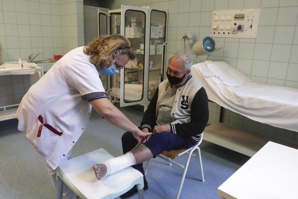 Medic Franciska Csortos examines a patient at the hospital for the homeless in Budapest, Hungary, Wednesday, April 14, 2021. A bitter conflict has emerged between Hungary’s right-wing government and the liberal leadership of the country's capital city over a hospital for the homeless that may soon have to close. The Budapest hospital provides medical and social services and shelter to more than 1,000 people annually. But the Hungarian government has ordered it to vacate the state-owned building it occupies. Budapest's mayor says the eviction will risk the lives of the hospital's homeless patients as Hungary struggles with a deadly COVID-19 surge. (AP Photo/Laszlo Balogh)