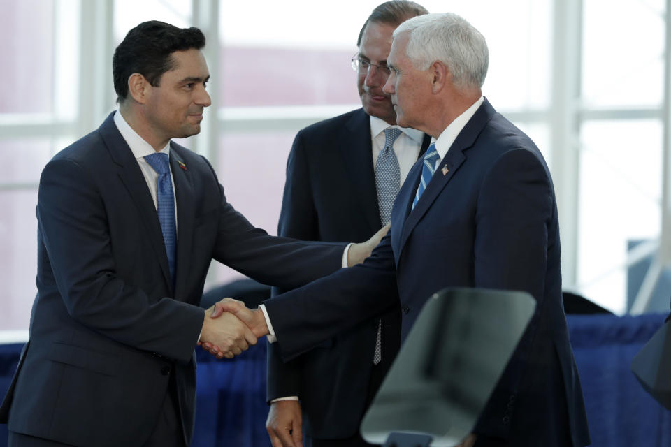 Vice President Mike Pence, right, shakes hands with Carlos Vecchio, ambassador to Washington for Venezuelan opposition leader Juan Guaido, left, following a tour on the USNS Comfort, Tuesday, June 18, 2019, in Miami. The hospital ship is scheduled to embark on a five-month medical assistance mission to Latin America and the Caribbean, including several countries struggling to absorb migrants from crisis-wracked Venezuela. At center is Secretary of Health and Human Services Alex Azar. (AP Photo/Lynne Sladky)