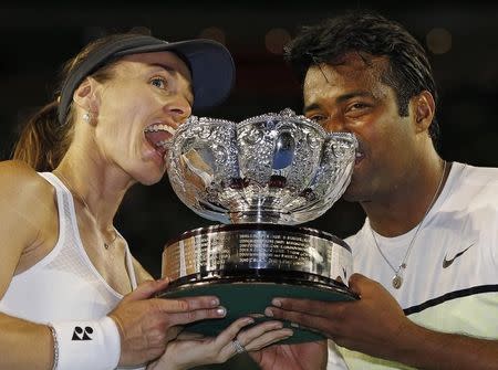 Martina Hingis (L) of Switzerland and Leander Paes of India bite their trophy after defeating Kristina Mladenovic of France and Daniel Nestor of Canada to win their mixed doubles final match at the Australian Open 2015 tennis tournament in Melbourne February 1, 2015. REUTERS/Issei Kato