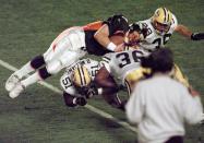 File-This Jan. 25, 1998, file photo shows Denver Broncos quarterback John Elway being flipped by Green Bay Packers' Brian Williams (51) and Elroy Butler (36) for a first down during Super Bowl XXXII at Qualcomm Stadium in San Diego. Members of a special panel of 26 selected all of them for the position as part of the NFL's celebration of its 100th season. All won league titles except Marino. All are in the Hall of Fame except Brady and Manning, who are not yet eligible. On Friday, Dec. 27, 2019, quarterback was the final position revealed for the All-Time Team. (AP Photo/Elaine Thompson, File)