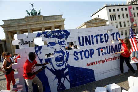 Campaigners pose on a 'United To Stop Trump' cardboard wall in front of the Brandenburg Gate to urge Americans living abroad to register and vote in Berlin, Germany, September 23, 2016. REUTERS/Axel Schmidt